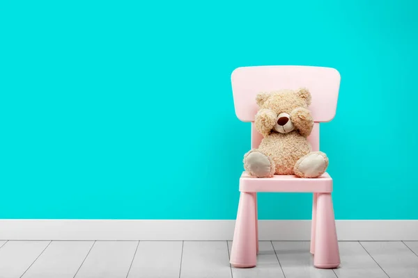 Un petit ours est assis dans une chambre turquoise sur une chaise les yeux fermés — Photo