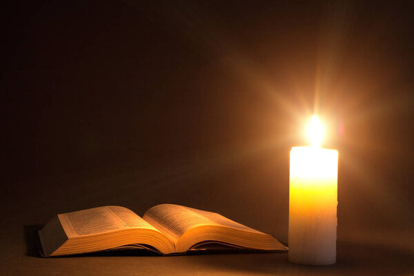 Bible on the table in the light of a candle