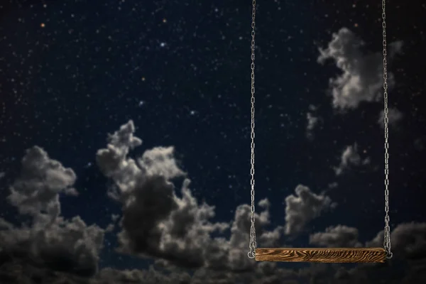 Een schommel op een nachtelijke hemel achtergrond — Stockfoto