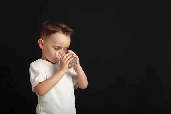 Kind trinkt Wasser auf schwarzem Hintergrund — Stockfoto