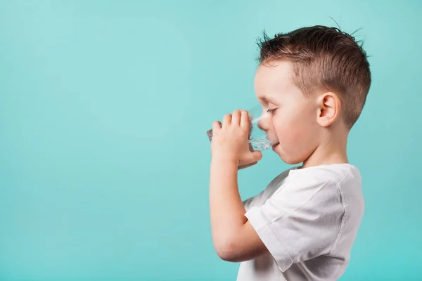 Dítě pije vodu na tyrkysové pozadí — Stock fotografie
