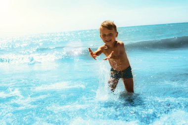 dalgalar ile deniz kıyısında çalışan bir çocuk