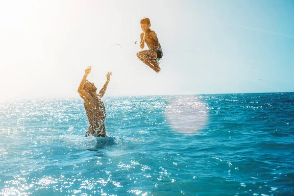 A Father throws his son into the sea. — Stock Photo, Image