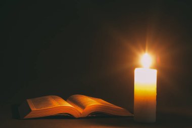 bir mum ışığında masada bir İncil