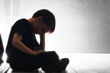Depresyondaki çocuk yerde oturuyor.