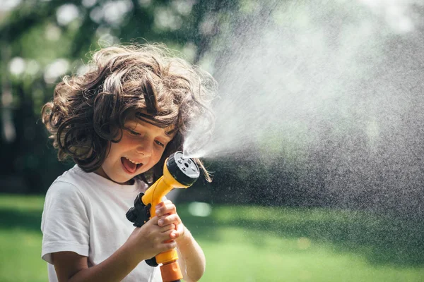 child plays with water in the backyard in the garden