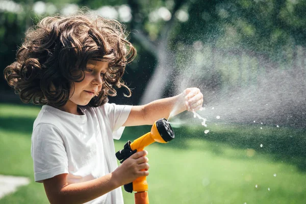 child plays with water in the backyard in the garden