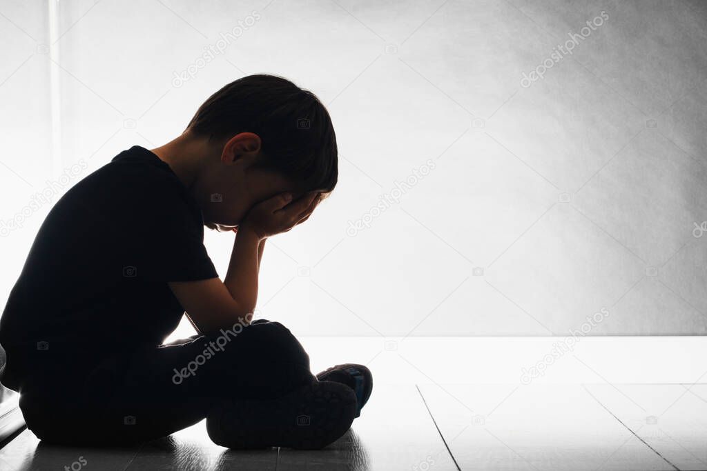 child with depression is sitting on the floor