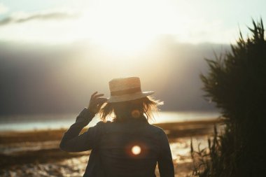 Günbatımında denizde meditasyon yapan bir kızı zorluyor.