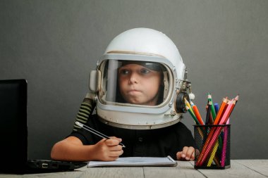 Çocuk, astronot kaskı takarak okulda uzaktan çalışıyor. Okula geri dön.