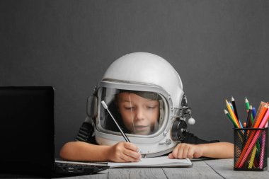 Çocuk, astronot kaskı takarak okulda uzaktan çalışıyor. Okula geri dön.