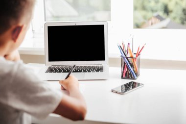 Evde okulda, online evde eğitim sayesinde. Çocuk bilgisayarın başında oturuyor.