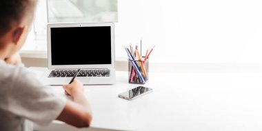 Evde okulda, online evde eğitim sayesinde. Çocuk bilgisayarın başında oturuyor.