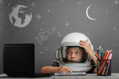 Çocuk, astronot kaskı takarak okulda uzaktan çalışıyor. Okula geri dön.