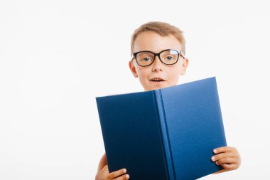 Çocuk parlak bir duvara karşı kitap okuyor.