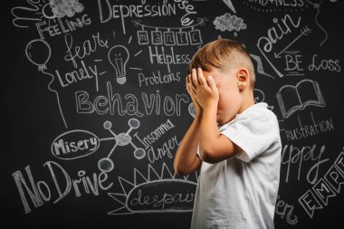 Depresyonu siyah arka planda elleri kapalı bir çocuk.