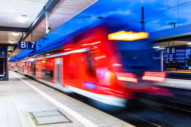 Yaratıcı soyut demiryolu seyahat ve demiryolu ulaşım sanayi kavramı: modern kırmızı yüksek hızlı elektrikli yolcu banliyö çift güverte tren hareket ile gece ışıklı istasyonu platformu, bulanıklık etkisi