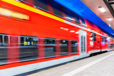 Yaratıcı soyut demiryolu seyahat ve demiryolu ulaşım sanayi kavramı: modern kırmızı yüksek hızlı elektrikli yolcu banliyö çift güverte tren hareket ile gece ışıklı istasyonu platformu, bulanıklık etkisi