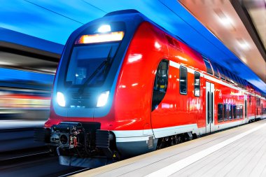 Yaratıcı soyut demiryolu seyahat ve demiryolu ulaşım sanayi kavramı: modern kırmızı yüksek hızlı elektrikli yolcu banliyö çift güverte tren hareket ile gece ışıklı istasyonu platformu, bulanıklık etkisi