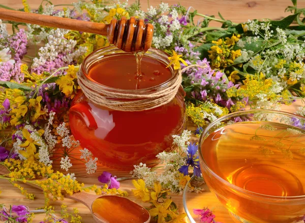 蜂蜜在玻璃罐子关闭与木勺子在花背景 — 图库照片