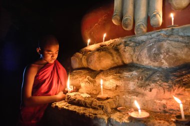 Bagan, Myanmar - Desember 8: eski pagoda tapınakta mandalay Tarih Parkı içinde Buddha statue yakınındaki mumlar ile dua genç Budist rahip. Desember 8, 2016, Myanmar