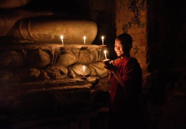 Bagan, Myanmar - Desember 8: Buda heykeli eski pagoda tapınakta mandalay Tarih Parkı içinde altında mumlar ile dua genç Budist rahip. Desember 8, 2016, Myanmar