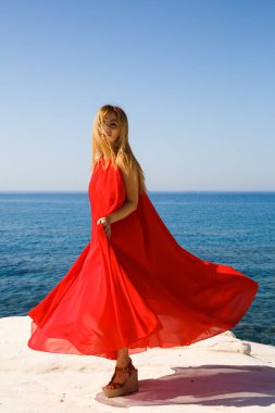 Kıbrıs'ta sahilde kırmızı elbiseli sarışın kadın.