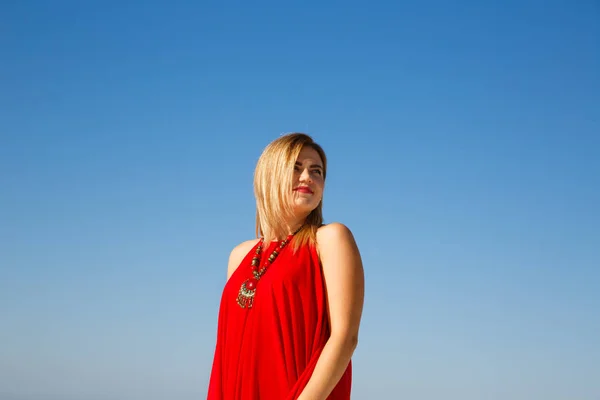Blond woman with necklace in the red dress.