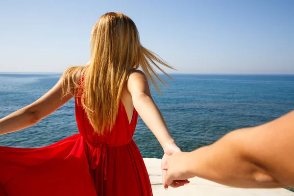 付いて来てください キプロスのビーチで友人の手を握って 赤いドレスの若いブロンドの女性 — ストック写真