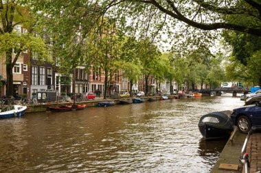 Amsterdam, Hollanda-18 Ağustos, 2015-Kanal tekneleri, binalar ve ağaçlar,, su manzaralı.