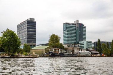 Amsterdam, Hollanda-18 Ağustos, 2015-Kanal tekneleri, binalar ve ağaçlar, denizden manzaralı.