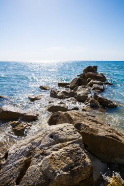Mavi Akdeniz parlak yüzeyi ve Kıbrıs'ta taşlar ile.