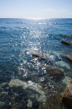 Mavi Akdeniz parlak yüzeyi ve Kıbrıs'ta taşlar ile.