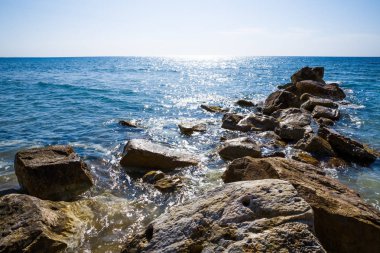 Mavi Akdeniz parlak yüzeyi ve Kıbrıs'ta taşlar ile.