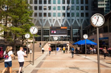 Londra, İngiltere - 26 Ağustos 2019 - Canary Wharf finans bölgesi şirket binaları ve saatleriyle. İş alanında yürüyen insanlar.