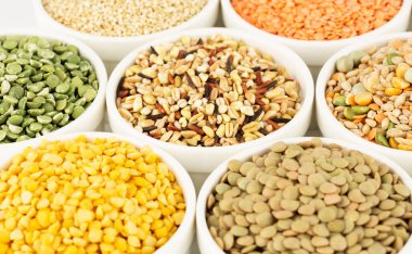 Beyaz seramik kaselerdeki farklı Groats koleksiyonu. Bezelye, renkli mercimek, buğday taneleri, pirinç, kinoa.