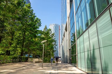 Londra, İngiltere - 26 Ağustos 2019 - Canary Wharf finans bölgesi kurumsal ofis modern binaları ile. Sokak lambalarının yanında yürüyen iki adam..