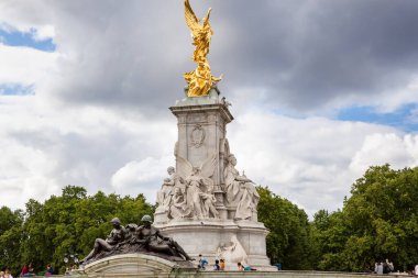 Londra, İngiltere - 8 Ağustos 2019 - Victoria Memorial 'ın etrafında mermer ve bronz heykellerle oturan turistler, Buckingham Sarayı' nın önündeki ikonik anıt..