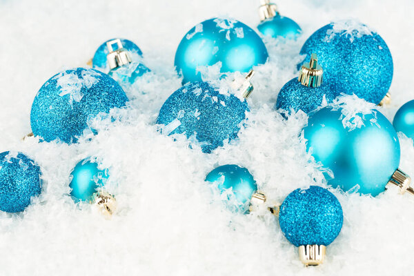 Christmas decoration with blue balls on the artificial snow background.