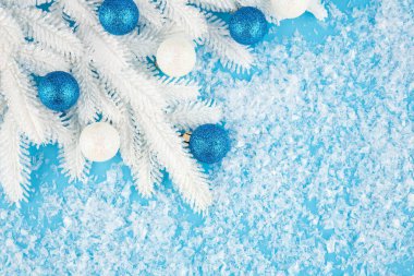 Yapay kar arka planında toplarla ve beyaz köknar dallarıyla Noel süslemesi.