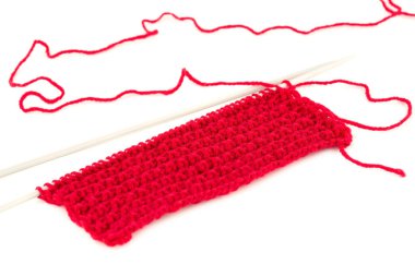 Beyaz arkaplanda örgü iğneleri olan kırmızı iplik..
