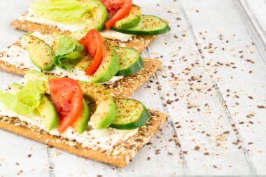 Kraker, peynir, avokado, salatalık, domates ve marullu sandviç..