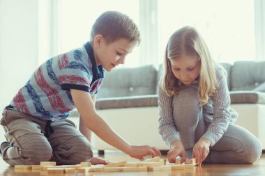 İki mutlu kardeşler sevinçle ahşap bloklar evde bir oyun oynuyor 
