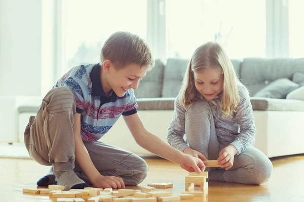 Dva Šťastní Sourozenci Hrát Hru Dřevěnými Bloky Doma Radostně — Stock fotografie