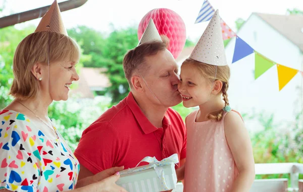 カラフルな装飾が施されたテラスでかわいい孫娘の誕生日を祝う幸せな祖父母の肖像画 — ストック写真