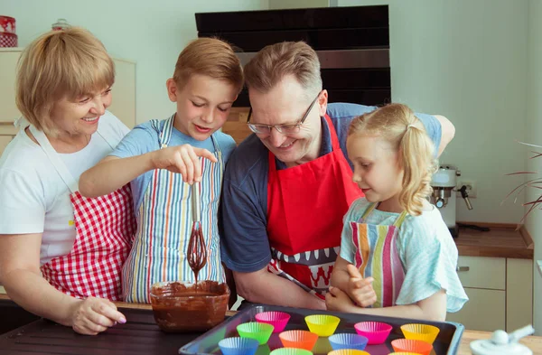 快乐的祖父母与他们的孙子们一起在现代厨房里准备巧克力松饼的乐趣 — 图库照片