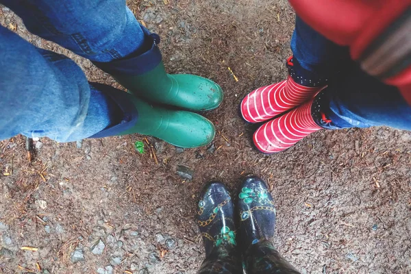 Three pairs of rubber boots at rainy autumn weather. View above