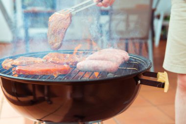 Biraz biftek, sosis ve sebze ızgara ızgara genç adamın elini