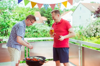 Mutlu arkadaşlar eğlenmeye ve onların konuşma ve içecekler bira sırasında ızgara et ve sebze teras keyfini çıkarın