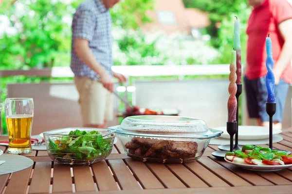 楽しい幸せな友達肉やテラスで野菜を焼くことの間に彼らの話や飲み物のビールをお楽しみいただけます — ストック写真